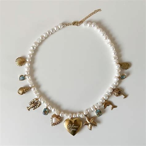 A White Necklace With Gold Charms And Shells Is Displayed On A White