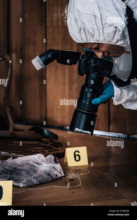 Crime Scene Forensics Expert Photographing Evidence At A Crime Scene