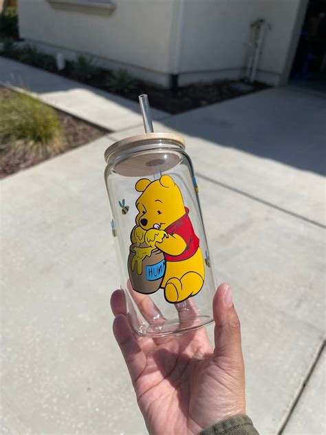 Someone Holding Up A Winnie The Pooh Tumbler