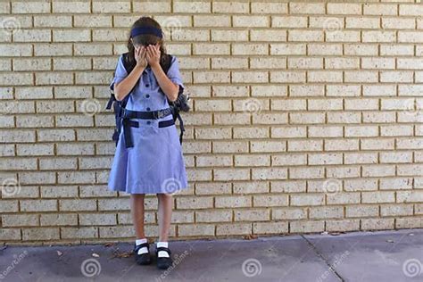 Sad Young Schoolgirl Covering Her Face And Crying In School Yard Stock