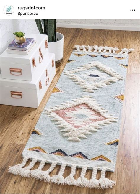 A Blue Rug With Tassels Is On The Floor Next To A White Dresser