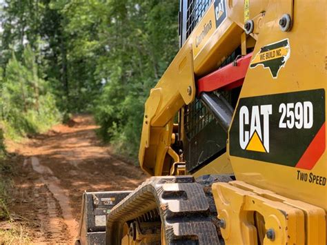 The Back End Of A Large Yellow Bulldozer Driving Down A Dirt Road Next