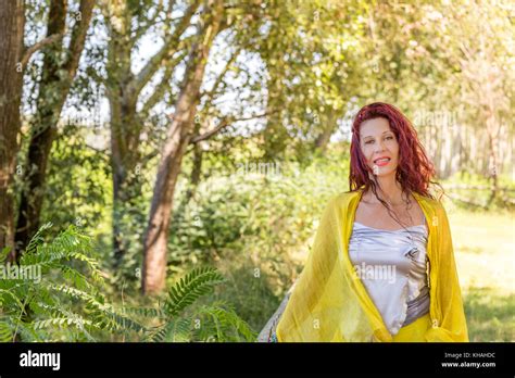 Portrait de femme mature allemande avec châle jaune et argent haut smiling dans un jardin