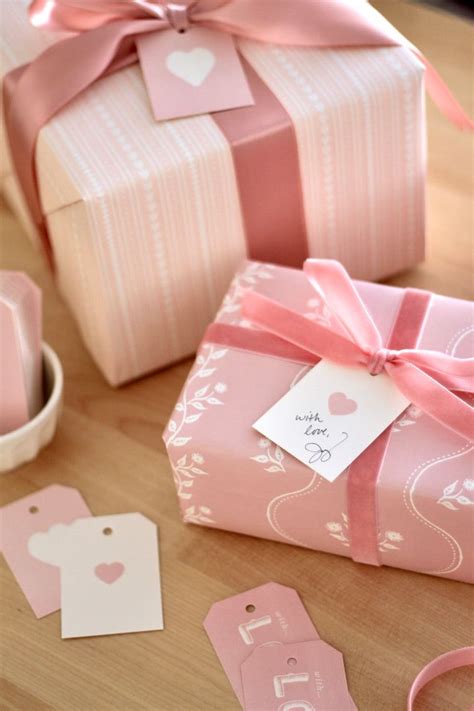 Pink Gift Boxes With Tags And Ribbons On Top Of A Wooden Table Next To