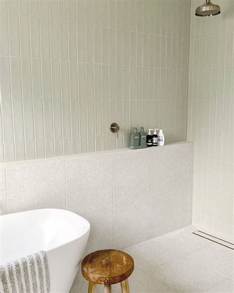 A White Bath Tub Sitting Next To A Wooden Stool