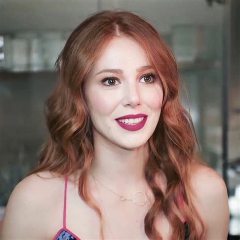 A Woman With Red Hair Is Looking At The Camera