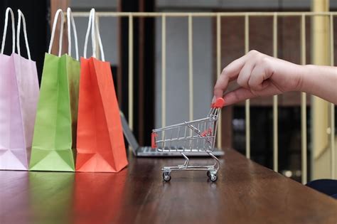 Premium Photo Cropped Hand Holding Shopping Cart By Bags On Table