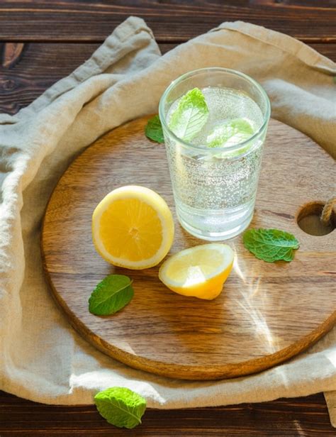 Газированная вода в стакане с разделочной доской, листьями и лимоном ...