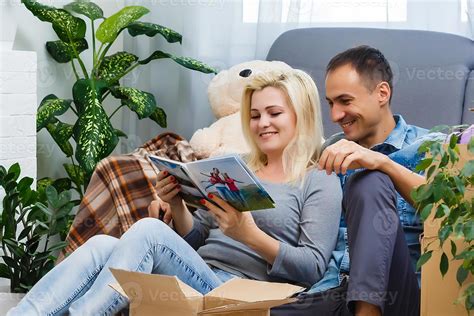 Young couple looking at family photo album.They sitting in living room ...