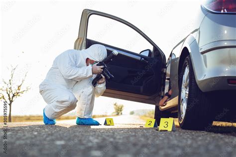 Detective Studying A Crime Scene Taking Photographs Stock Photo