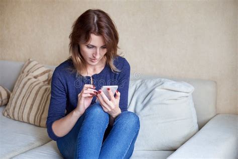 Attractive Young Woman Talking On Mobile Phone And Smiling At Home