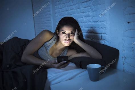 joven hermosa mujer latina en la cama tarde en la noche mensajes de texto utilizando el teléfono