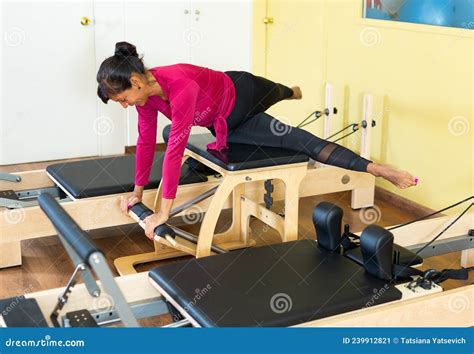 Active Hispanic Woman Practicing Pilates On Reformer In Fitness Studio