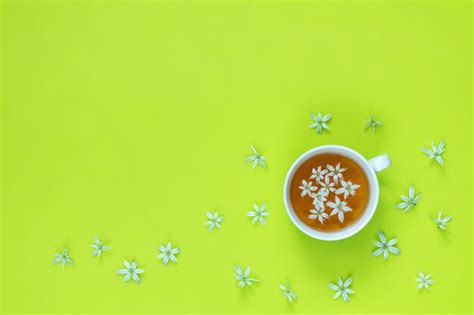 Premium Photo | Cup of tea with white flowers on bright green surface ...