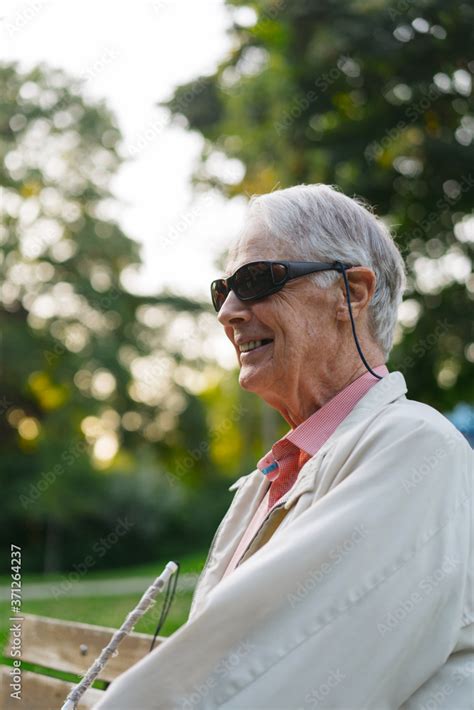 Visually Impaired Older Man Sitting On Bench In Nature Stock Photo