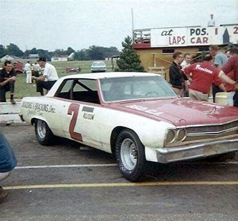 An Old Red And White Car Parked In A Parking Lot Next To Other Cars