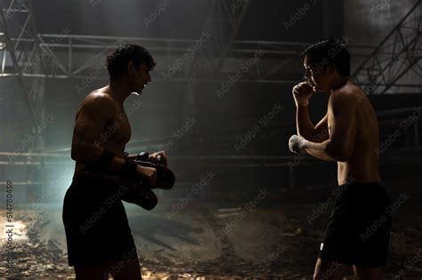 Strong Asian sportsman practicing boxing workout punching with male ...