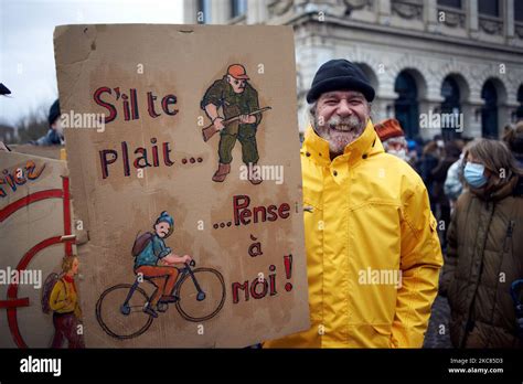 A Man Holds A Placard Depicting A Hunter And A Cyclist And Reading