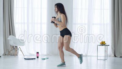 Side View Of Slim Woman Doing Single Leg Squats With Dumbbells In Hands