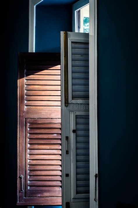 Shuttered Window With One Pane Open Letting Through Rays Of Light Stock