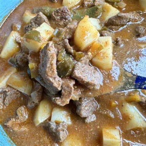 A Blue Bowl Filled With Stew And Potatoes