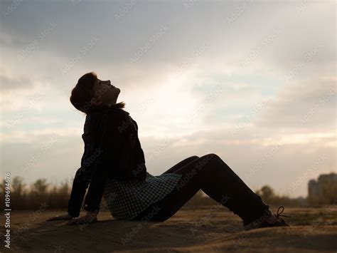 Young Teen Girl Sitting On The Ground And Looking Up At The Sky The