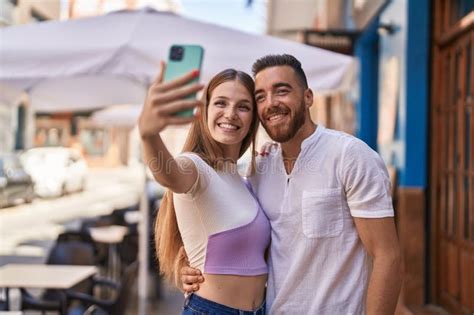 Pareja De Hombres Y Mujeres Sonriendo Confiados Hacen Selfie Por