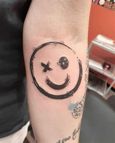 a person with a tattoo on their arm that has a smiley face in the middle