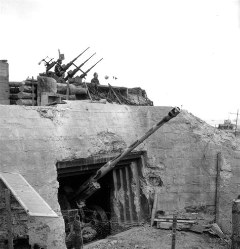 A damaged German bunker, still home to a PaK 43 field gun derived from ...