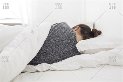 Young woman lying down in bed stock photo - OFFSET