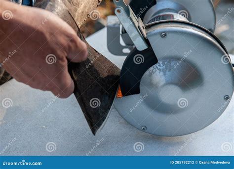 Close-up of Men`s Hands Sharpening an Axe on an Electric Sharpener ...