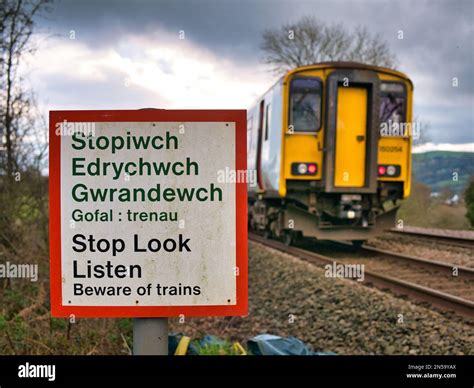 A Train Passes A Warning Sign Saying Stop Look Listen In Welsh And