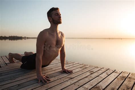 El Deportista Joven Hermoso Hace Ejercicios De La Yoga En La Playa