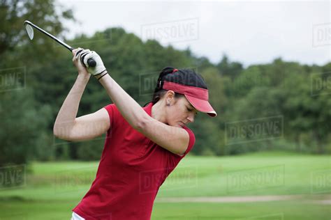 A female golfer preparing to swing her club - Stock Photo - Dissolve