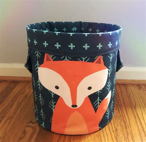 A Blue And Orange Fabric Basket With A Fox On Its Side Sitting On A