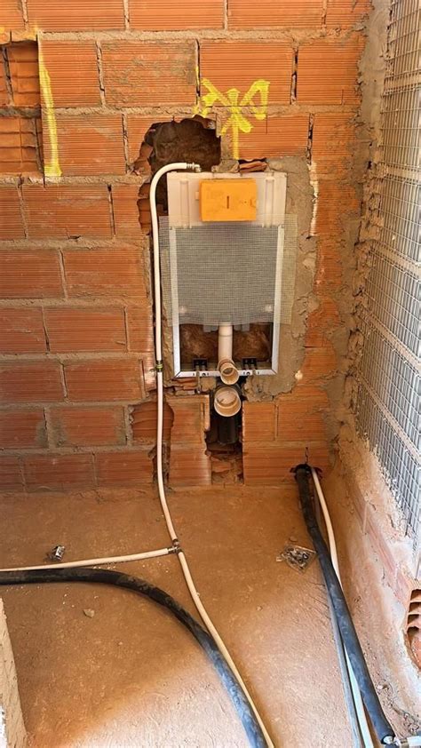 An Air Conditioner In The Corner Of A Room With Exposed Pipes And Brick