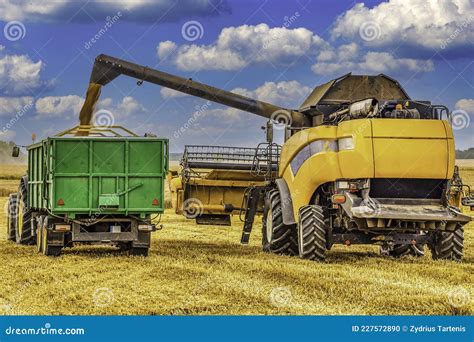 Combine Harvester Unloading Grain Into The Tractor On The Agricultural