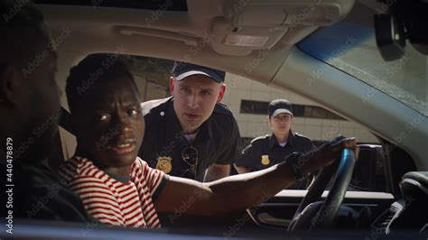 Serious police officer checking black men in car Stock Photo | Adobe Stock