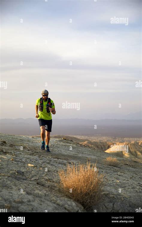 Runner Athlete With Backpack Running On The Wild Trail At Red Mountains