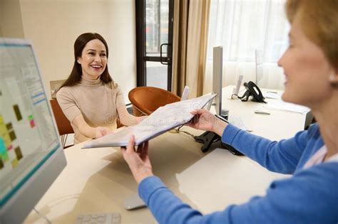 Two Female Recruiters Looking Through A Folder With Resume Documents Of