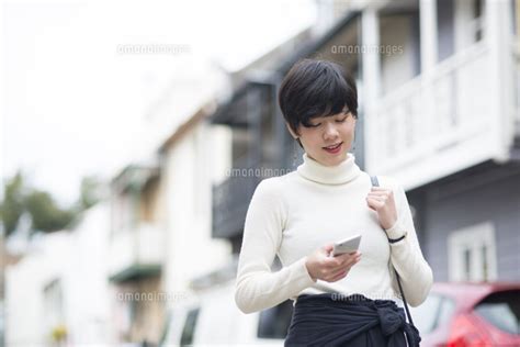 街でスマホを見ている女性 10568004079 の写真素材・イラスト素材｜アマナイメージズ