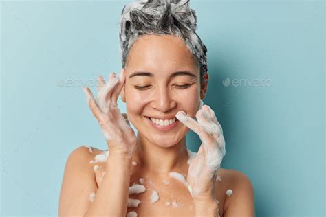 Pleased Young Brunette Asian Woman Washes Hair Applies Shampoo Smiles Gently Keeps Eyes Closed