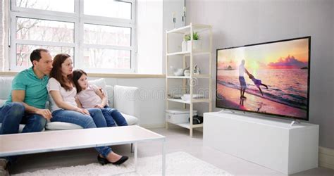 Young Family Watching TV Together Stock Image - Image of women, television: 276495459