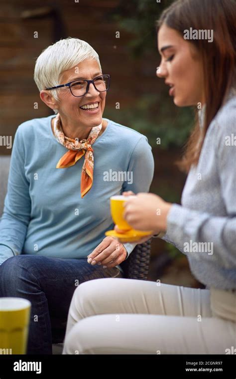 Old Cheerful Mother And Young Adult Daughter Talking Drinking Coffee