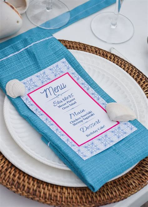 A Place Setting With Blue Napkins And Seashell On It Along With Wine