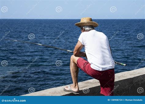 Pescador En La Costa Un Hombre En Un Pescado Blanco De Las Capturas Del