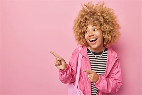 Una mujer sonriente y alegre señala con el dedo índice hacia el lado