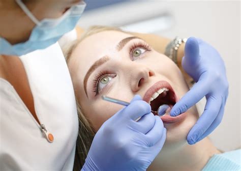 Dentista Feminina Verificando Os Dentes Da Mulher Do Paciente Foto