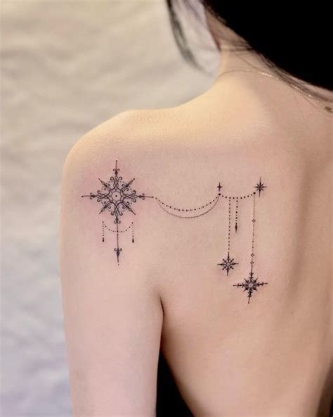 The Back Of A Woman S Shoulder With A Star And Chain Tattoo On It