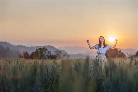 Mujer divirtiéndose en el campo de cebada al atardecer Foto Premium